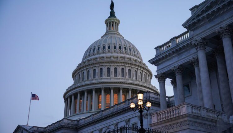 U.S. Capitol dome at twilight with illuminated windows, flag flying to the left, and a decorative lamp in the foreground.”