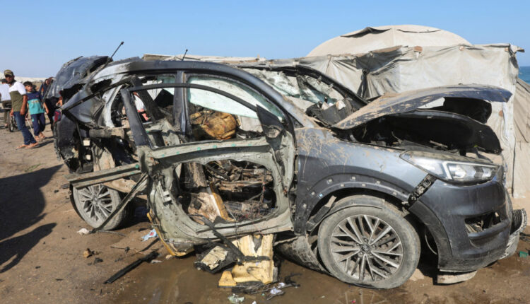 Palestinians stand near the site of an Israeli strike on a vehicle in Khan Younis